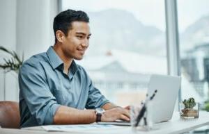 A business administration professional sitting at a desk in front of a laptop.